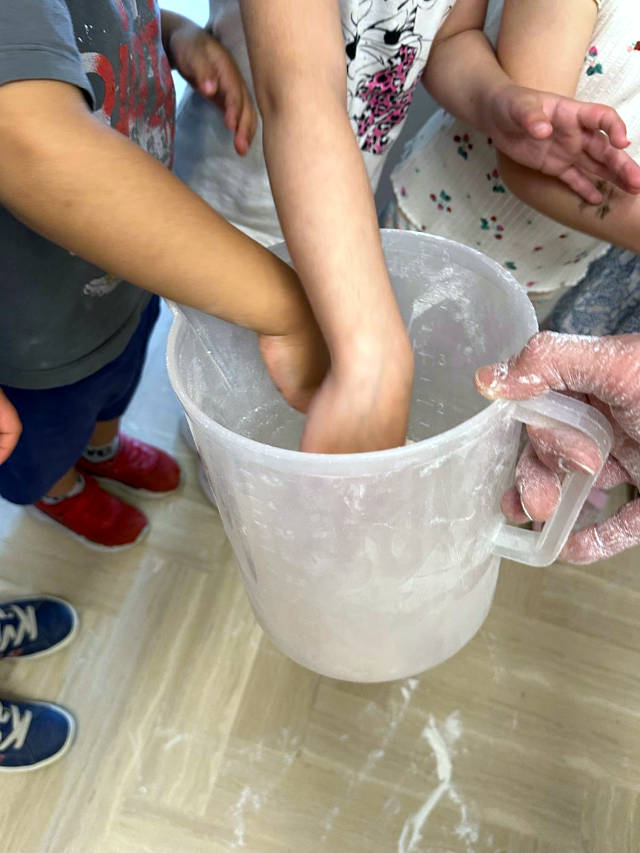 Mani dei bambini immerse nella farina durante il laboratorio