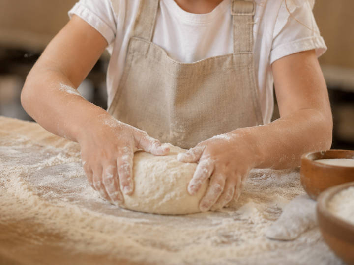 Mani di una bambina impegnata in un laboratorio di panificazione